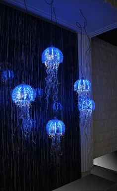 some blue lights hanging from the ceiling in front of a black wall with white curtains