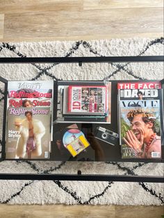 magazines are sitting on top of a glass table with an iron frame and black legs