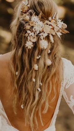 the back of a woman's head with white flowers in her hair and long curly hair