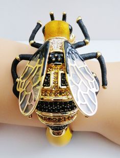 "WOW! Stunning french designer Fifilapin huge enamel crystal bee bracelet with glass wings.Fabulous, true statement bumble bee bracelet done with black and gold enamel, pave crystals in clear,black, and topaz, glass wings with gold tone framing with side hinge. Bee meets up with white, yellow, and blue enameled flower. Measures 2 1/4\" across interior. Even the interior is enameled.Resembles famous Designer Pasotti from Italy. Bee measures 3\"L X 2 1/4\"W. Signed Fifilapin. Mint condition. A bee Glass Wings, Bee Bracelet, Angel Brooch, Famous Designer, French Designer, Famous Designers, Yellow And Blue, Gold Enamel, French Design