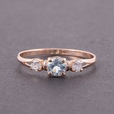 an engagement ring with three stones on the side and one stone in the middle, sitting on a gray surface