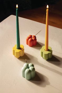 three candles are sitting on a table with tomatoes and peppers in the middle one is lit