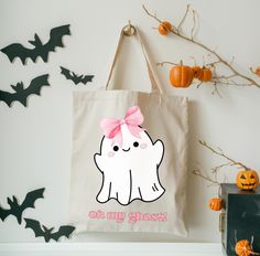 a bag with a pink bow on it sitting next to some bats and pumpkins