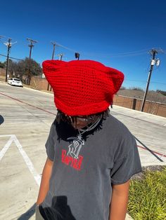 a person wearing a red knitted hat on top of their head in a parking lot