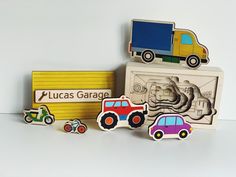 three wooden magnets with cars and trucks on them next to a sign that says lucas garage