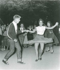 an old black and white photo of two people dancing in front of a group of people