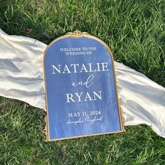 a wedding sign laying in the grass next to a white cloth on top of it