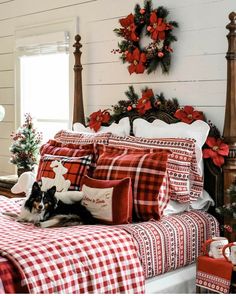 a dog is laying on a bed with red and white plaid sheets, christmas decorations and wreaths