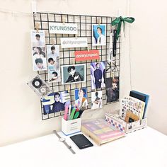 a white desk topped with lots of pictures and magnets next to a cell phone