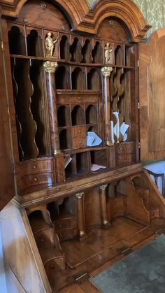 an old wooden desk with many drawers and cupboards on it's sides, in the corner of a room