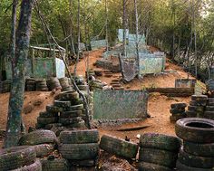 old tires are piled up on the ground in an area with lots of trees and dirt