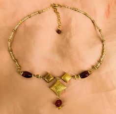 Etruscan style necklace with real red agate stones, composed of three central golden and finely decorated elements, with a pendant red agate stone, the necklace is also composed of 2 tall agate stones and small golden glass beads. It ends with a golden steel chain to adjust the length. This is a very precious necklace and is a reproduction inspired by jewels in Etruscan art museums. It is a jewel handmade in Italy with attention to every detail. Hypoallergenic golden steel locking hook Etruscan Artisan Gold Carnelian Jewelry, Artisan Carnelian Gold Jewelry, Handmade Garnet Beaded Necklaces, Handmade Garnet Bead Necklaces, Gold Beaded Ruby Necklace, Handmade Garnet Necklaces With Round Beads, Handmade Ruby Necklaces With Spiritual Style, Handmade Ruby Necklace For Gift, Gold Ruby Necklaces With Polished Beads