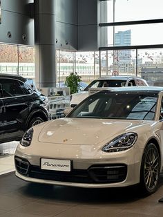 two porsches are on display in a showroom, one is white and the other is black