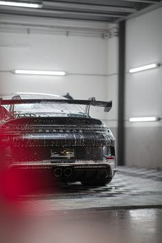 a black sports car parked in a garage with its hood up and the lights on