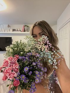 a woman holding a bunch of flowers in her hands