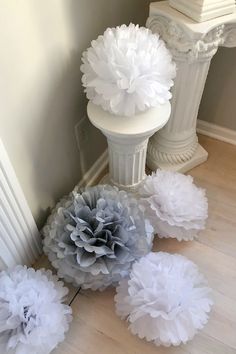 some white and grey paper flowers on the floor next to a pillar in a room