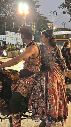 a man and woman riding on the back of a motorcycle