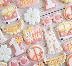 decorated cookies are arranged on a table with peace signs, flowers, and cars in the background