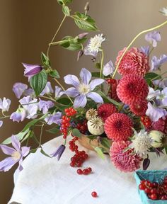 a vase filled with lots of flowers on top of a white tablecloth covered table