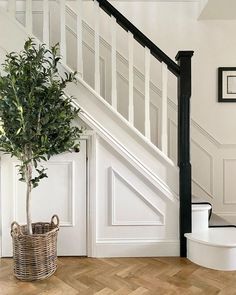 a plant in a basket sitting on the floor next to a stair case and banister