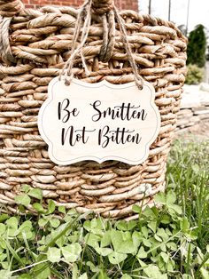 a basket with a sign that says be smitten not bitten on it in the grass