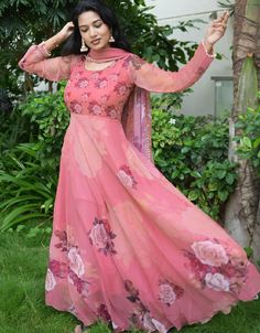 a woman in a long pink dress with flowers on the bottom and sleeves, is posing for