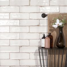 a vase with flowers on top of a shelf next to a wall mounted soap dispenser