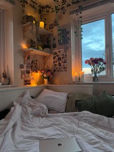 a laptop computer sitting on top of a bed in a bedroom next to two windows