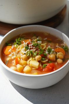 a white bowl filled with soup next to a pot full of food on top of a table