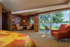 a bedroom with a bed, chair and large window overlooking the lake in front of it