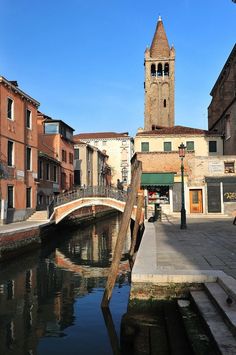 a bridge over a small river in the middle of a town with buildings on both sides