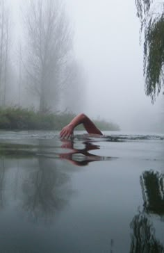 a person laying on their back in the middle of a body of water surrounded by trees