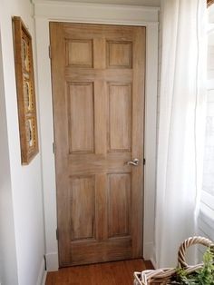 a wooden door in a white room next to a basket with flowers on the floor