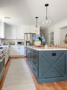 a kitchen with blue cabinets and white counter tops, an island that has flowers on it