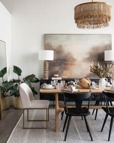 a dining room table with chairs and a painting on the wall