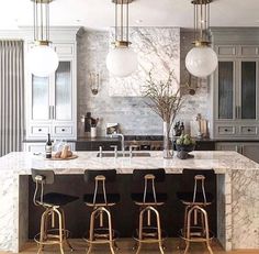 a kitchen with marble counter tops and stools in front of an island that has four bar stools on it