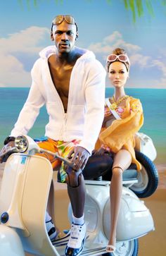 a man and woman sitting on a scooter in front of the ocean with palm trees