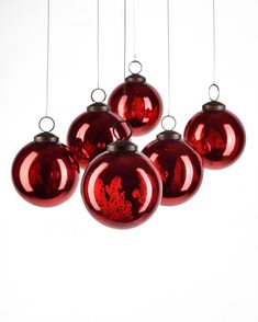 six red ornaments hanging from strings against a white background