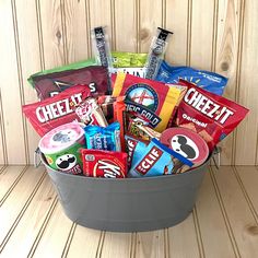 a bucket filled with candy and snacks on top of a wooden table next to a wall