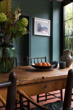 a bowl of fruit is sitting on a wooden table in front of a large window