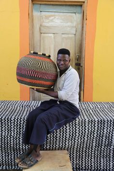 a man sitting on top of a bed holding a large woven basket over his head