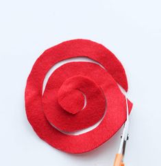 a pair of scissors and a red felt hat on a white surface with the shape of a spiral