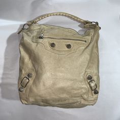 beautiful, authentic, BALENCIAGA cream distressed goat skin leather Moto City Day Bag. Features signature buckle and mesh stud detailing at the front, single whipstitched leather strap at the shoulder. Fully liked in black cotton, with one interior sidewall zip secure pocket. Includes sleeper bag and original BALENCIAGA mirror. VERY GOOD PRE-OWNED CONDITION, shows normal use appropriate signs of wear and tear including patination to the leather from being handled, light dirt marks to exterior from normal use and light ink mark or two at exterior which are not noticeable unless looking for them. APPROXIMATE MEASUREMENTS 16" x 5" x 13" 10" Strap drop MADE IN ITALY RETAIL $2600 Leather Moto, Day Bag, Black Cotton, Goats, Bags Handbags, Balenciaga, Leather Straps, Shoe Accessories, In Italy