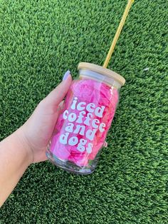 a hand holding a cup with pink tissue paper on it that says iced coffee and dog