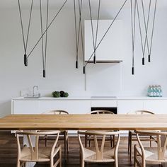 a wooden table surrounded by chairs in a room with white walls and wood flooring