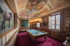 a room with a pool table and paintings on the wall