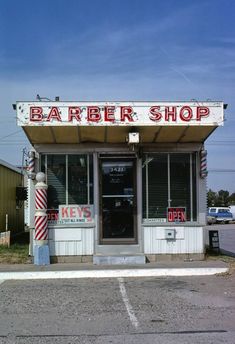 an old fashioned barber shop sitting on the side of a road