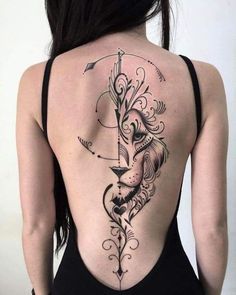 the back of a woman's body with an arrow and lion tattoo on it