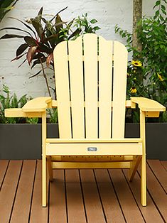 a yellow lawn chair sitting on top of a wooden deck next to potted plants