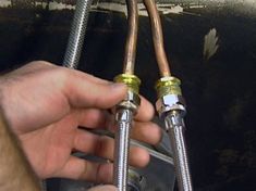 a man is working on an air conditioner with two hoses attached to it